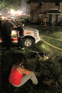 A woman watch as firefighters work to fight the blaze in July. Credit: Tom Sofield/LevittownNow.com