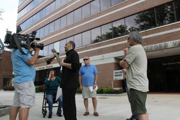 Protester John P talks to a television cameraman about the gathering. Political action committee MoveOn.org backed the protest and had opposed the end of net neutrality.   Credit: Tom Sofield/LevittownNow.com