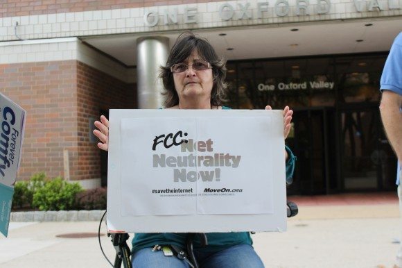 Debi Smith sits outside the FCC offices in Middletown on Thursday afternoon. Protesters said security barred them from going to the local FCC office.  Credit: Tom Sofield/LevittownNow.com