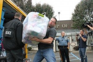 Detective Steven Reeves carries a box of items retrieved from the stolen store. Credit: Tom Sofield/LevittownNow.com