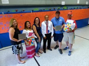 (Left-right) Herbert Hoover ES PTO members Lauren Eckert, Melissa Devine, Kelly Rooney and Principal Michael Rodriguez; Kids Club staff members Chuck Inverso and Jim McPartlin at the dedication ceremony for the new traverse wall mats (seen behind the group) and an outdoor picnic area. Credit: Neshaminy School District