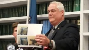 The district attorney holding up a photo of the two pellet guns and the customer's real gun. Credit: Tom Sofield/LevittownNow.com